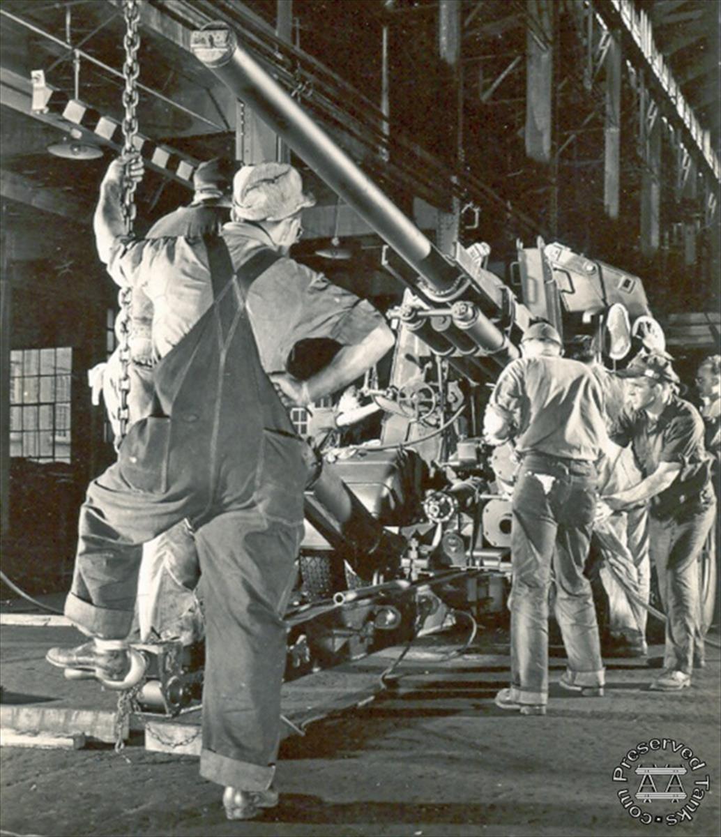 “This photograph of Allis-Chalmers employees at the La Porte Works shows a World War II scene typical of U.S. factories. Having converted to war production from their regular line of agricultural harvesting equipment, Allis-Chalmers was busy with government contracts for machinery to be used in the war effort. In this view, the workers are shown finishing a 90 m.m. gun.”, photo and caption from LaPorteCountyHistory.org